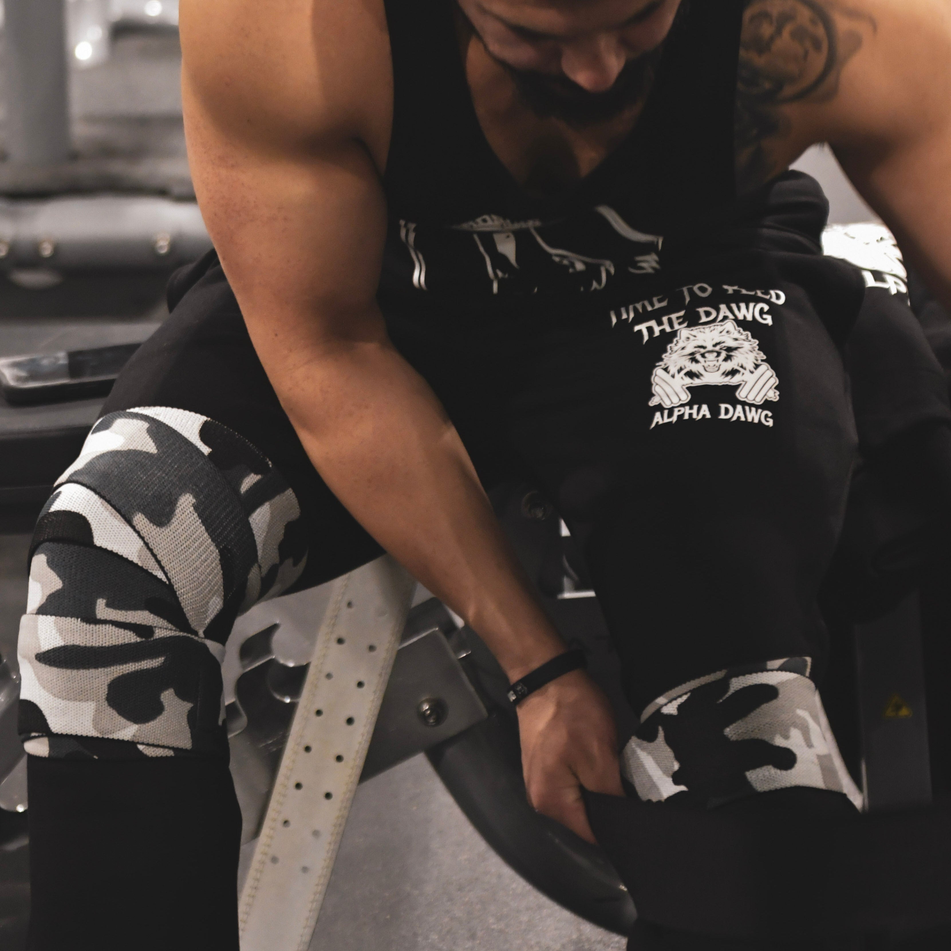 Person in gym wearing headphones and a tank top with a logo.